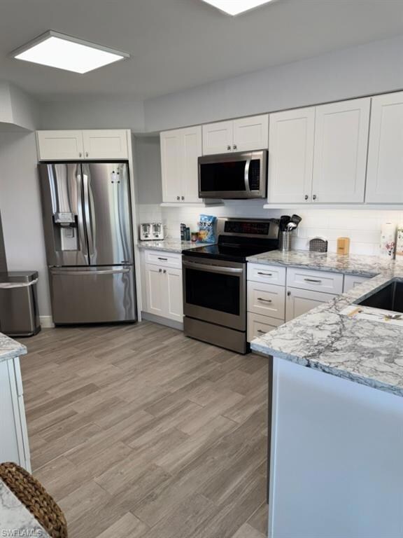 Kitchen featuring a sink, light stone counters, ap