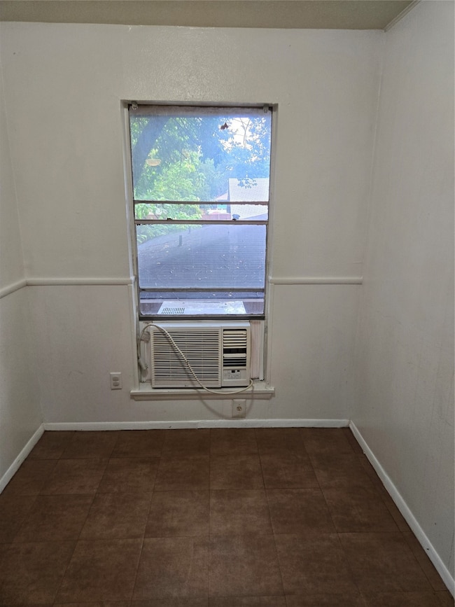 Spare room featuring baseboards and dark tile patterned floors