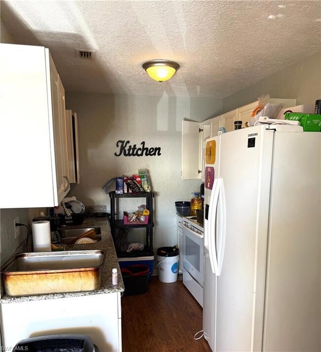 Kitchen featuring a textured ceiling, white applia