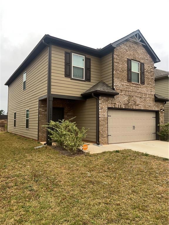 View of front of home featuring brick siding, a garage, a front lawn, and concrete driveway