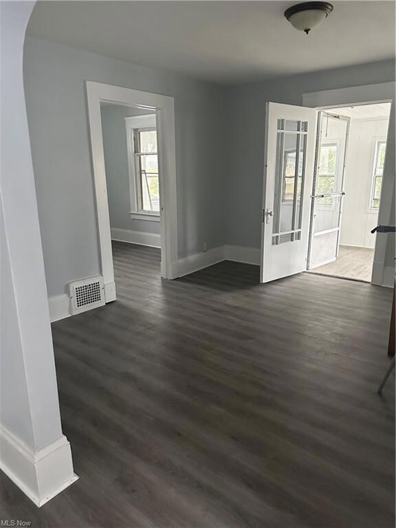 Unfurnished room featuring plenty of natural light and dark hardwood / wood-style floors