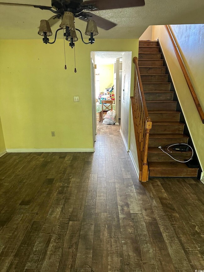 Staircase featuring ceiling fan, wood-type floorin