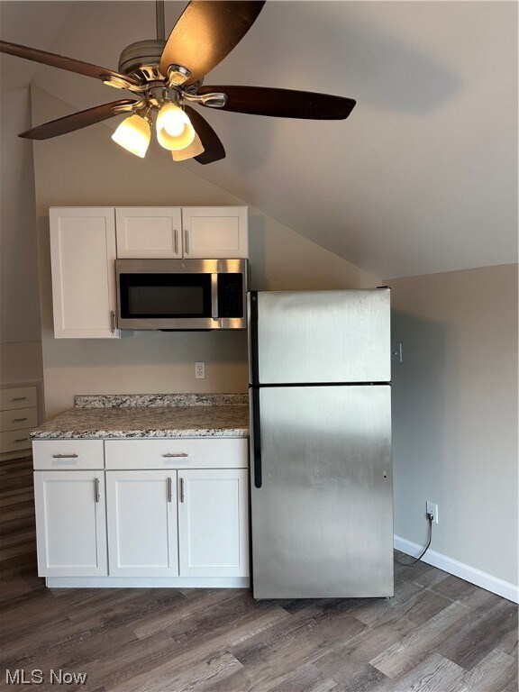Kitchen featuring dark wood-type flooring, white cabinets, stainless steel fridge, and ceiling fan
