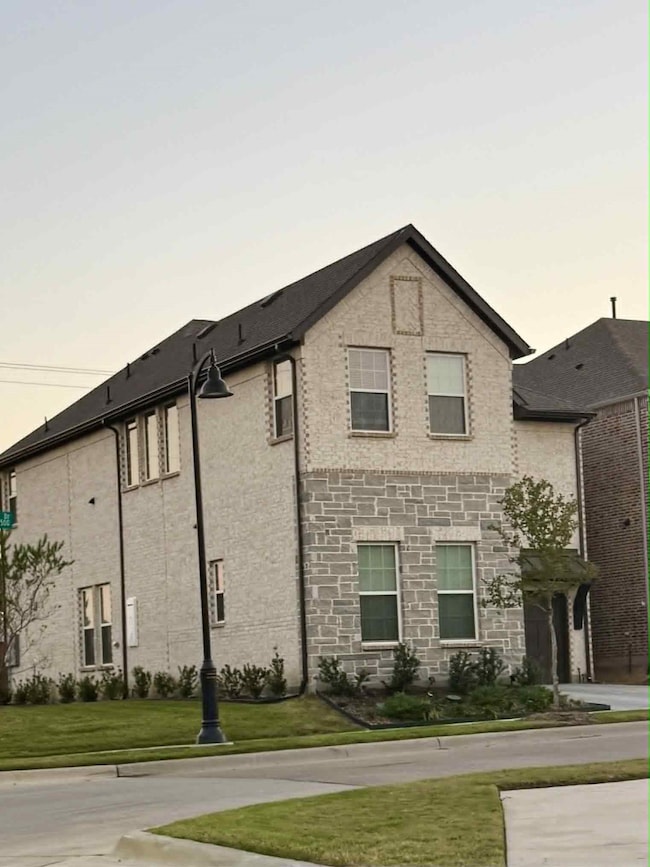 View of side of property featuring brick siding, a lawn, and stone siding