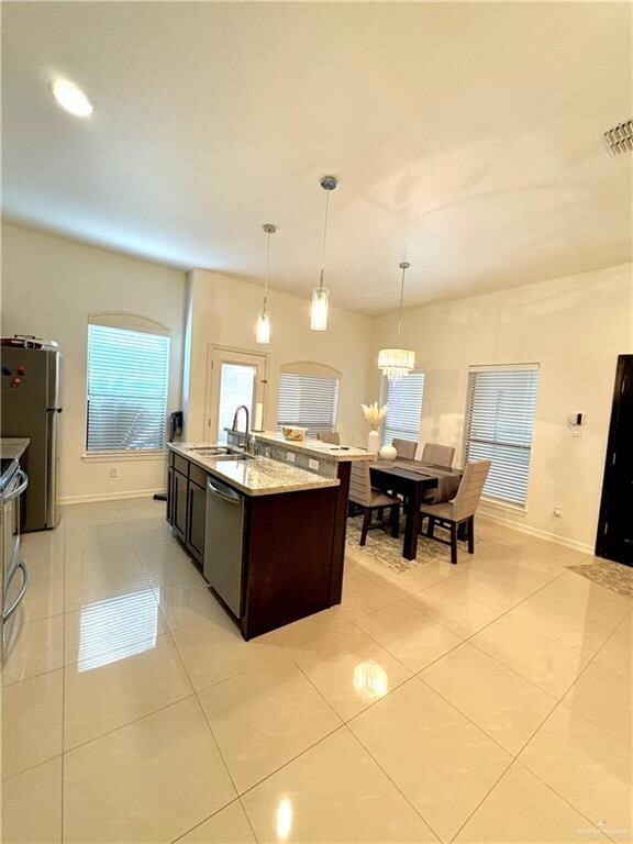 Kitchen with pendant lighting, sink, stainless steel appliances, and light tile patterned flooring