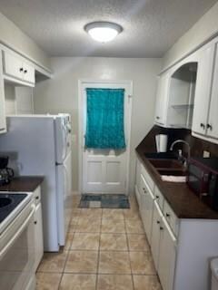 Kitchen with dark countertops, white cabinets, a s
