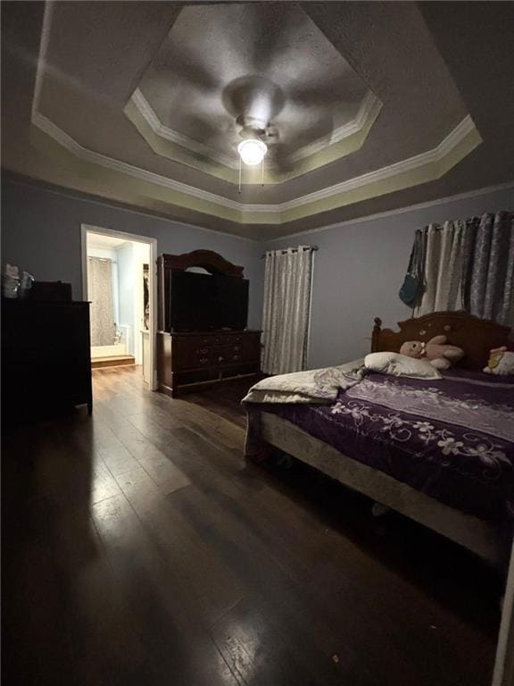 Bedroom with ornamental molding, a raised ceiling, dark wood finished floors, and a ceiling fan