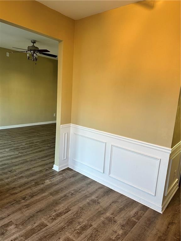 Unfurnished room featuring a ceiling fan, a wainsc