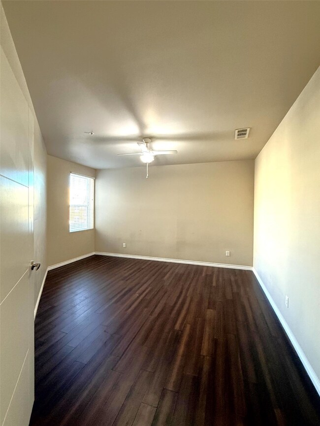 Empty room featuring dark wood-style floors and ceiling fan
