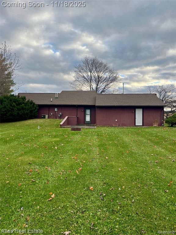 Back of house featuring roof with shingles and a yard