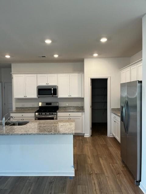 Kitchen with range, fridge, white cabinetry, light stone counters, and dark wood finished floors