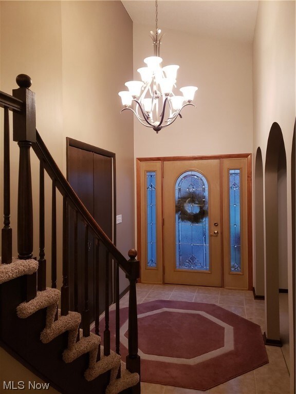 Tiled entryway with an inviting chandelier and high vaulted ceiling