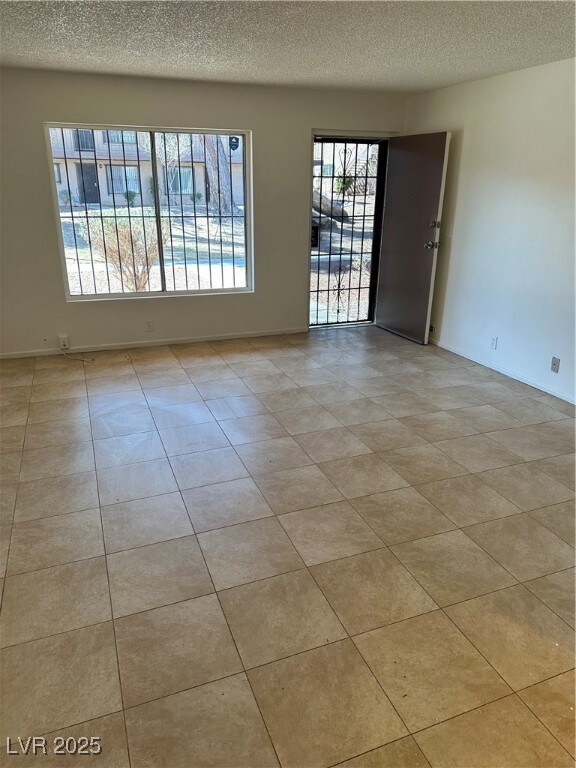 Empty room with a textured ceiling and light tile