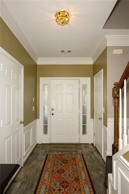 Entrance foyer with ornamental molding, a decorative wall, stairway, and wainscoting
