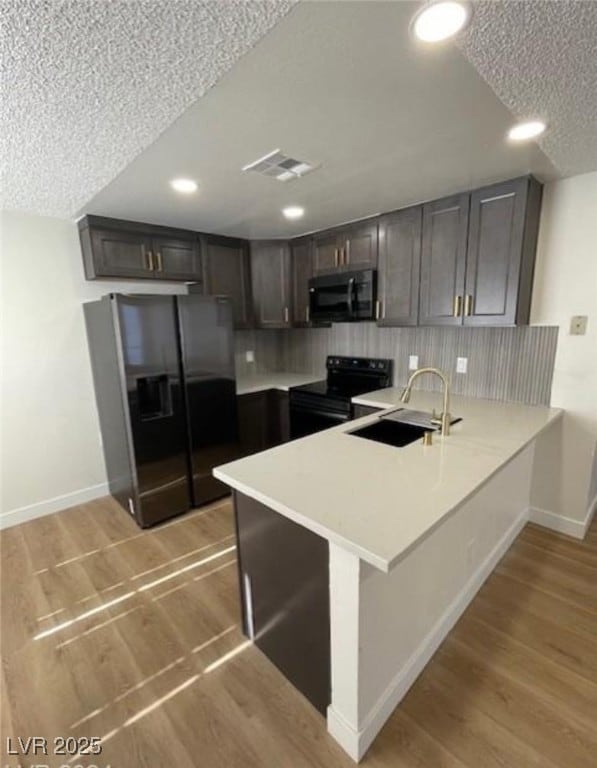 Kitchen with black appliances, a peninsula, light