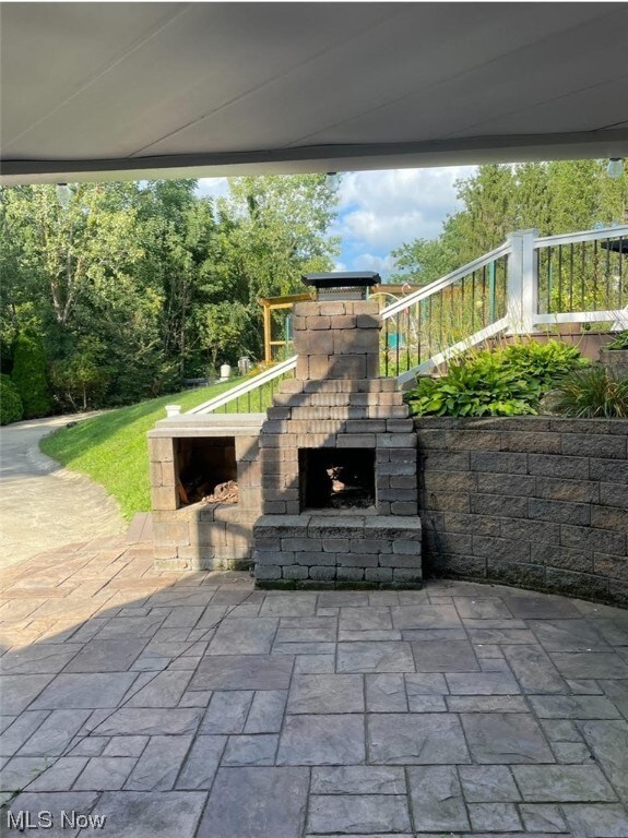 View of patio featuring an outdoor stone fireplace
