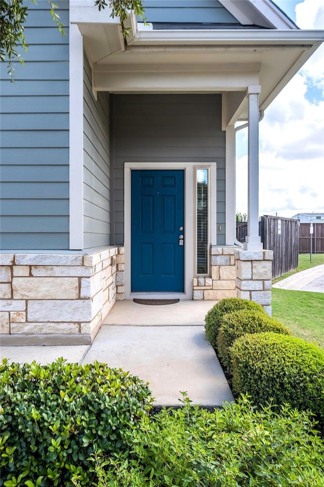 View of exterior entry with stone siding and a po