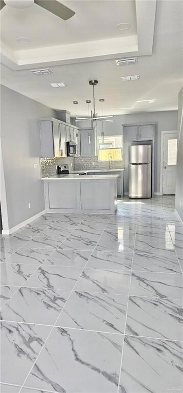 Kitchen featuring stainless steel appliances, gray cabinetry, light countertops, and light marble finish flooring