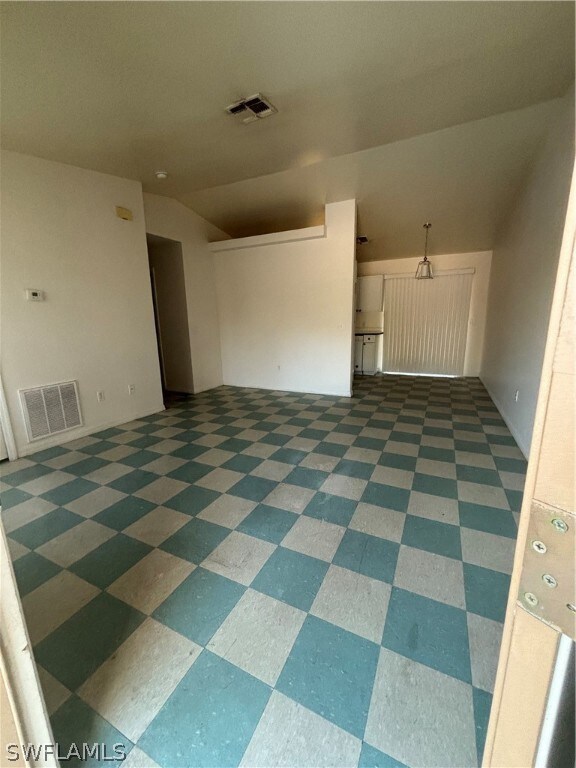 Tiled empty room featuring lofted ceiling