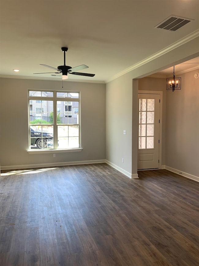 Great room with crown molding, a chandelier, LVP wood flooring, and ceiling fan
