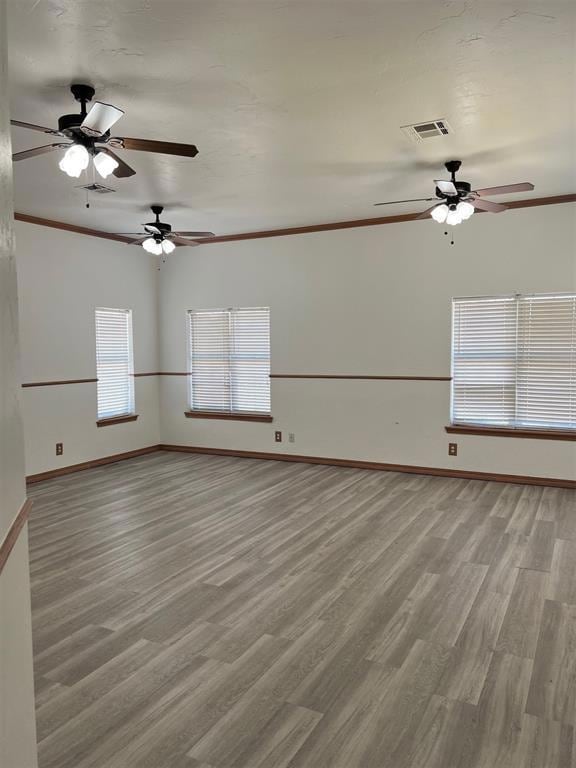 Empty room featuring visible vents, crown molding, and wood finished floors