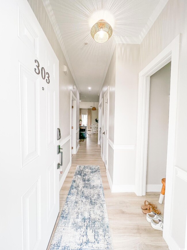 Corridor featuring crown molding and light hardwoo