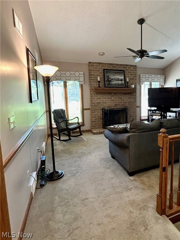 Living room with carpet flooring, ceiling fan, and a fireplace