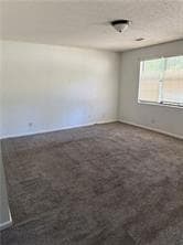 Unfurnished room with dark carpet and baseboards