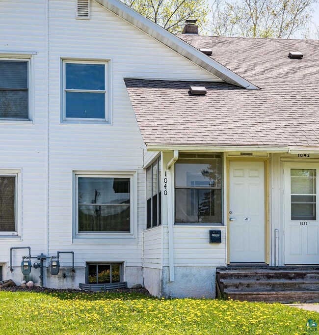 View of exterior entry featuring roof with shingles, a chimney, and a yard