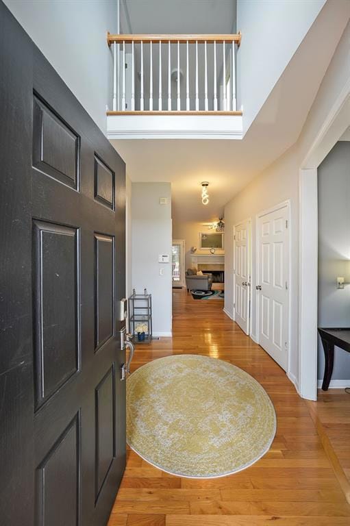 Foyer entrance with light wood finished floors, a high ceiling, and baseboards