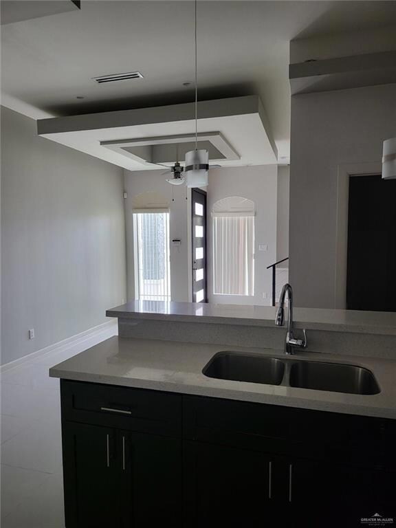 Kitchen featuring ceiling fan, dark cabinetry, and open floor plan