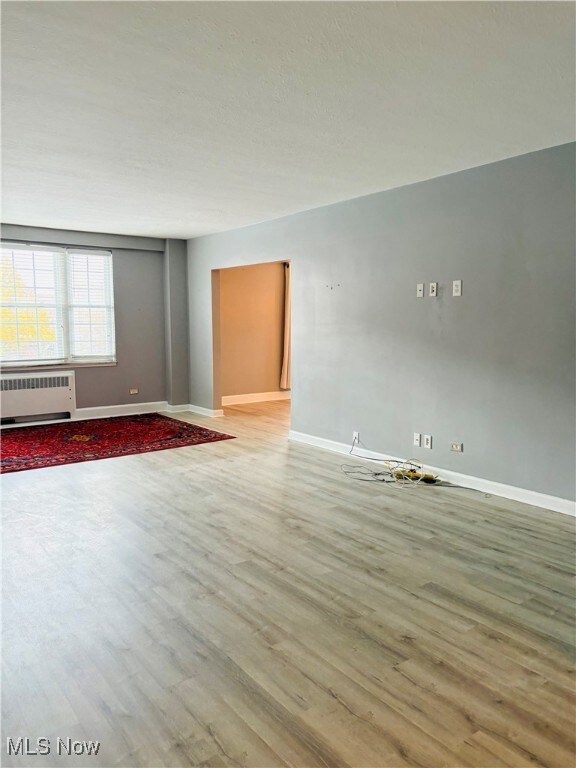 Living room with wood type finished floors, radiator, and a textured ceiling