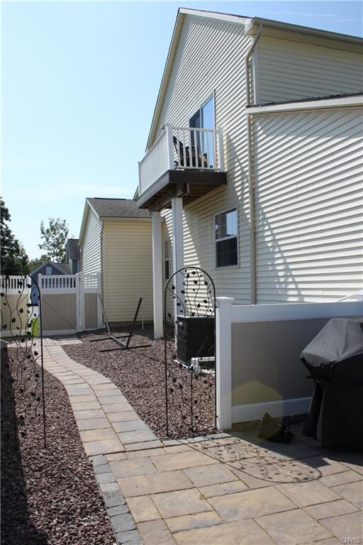 A Side View of the Home Showing the Hidden A/C Unit, Pool Filter, Access Gate to Front Yard, and the Balcony off the Owner's Suite Above.