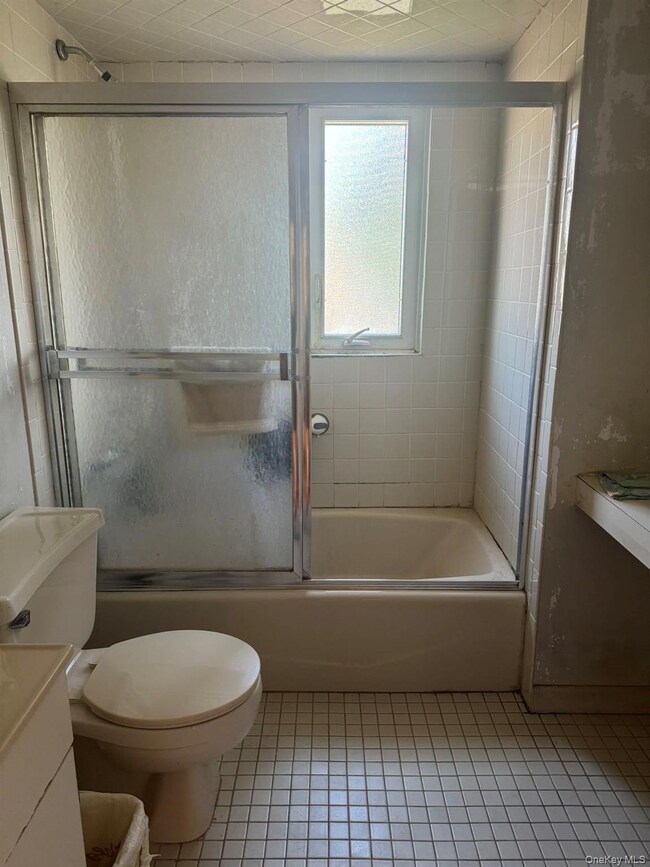 Bathroom featuring shower / bath combination with glass door, light tile patterned flooring, and vanity