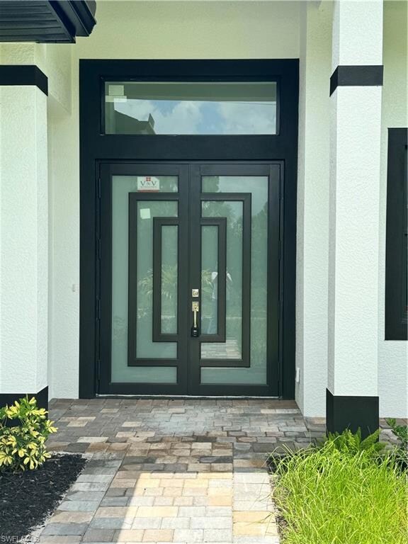 Doorway to property with stucco siding and french doors