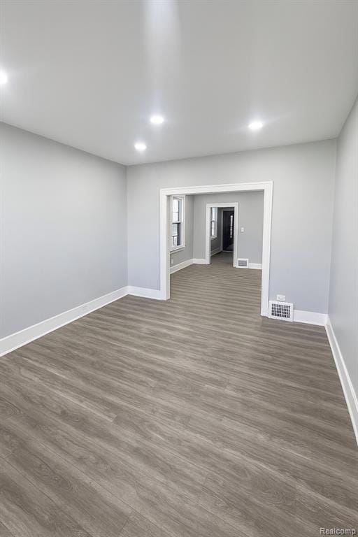 Empty room with dark wood-type flooring and recessed lighting
