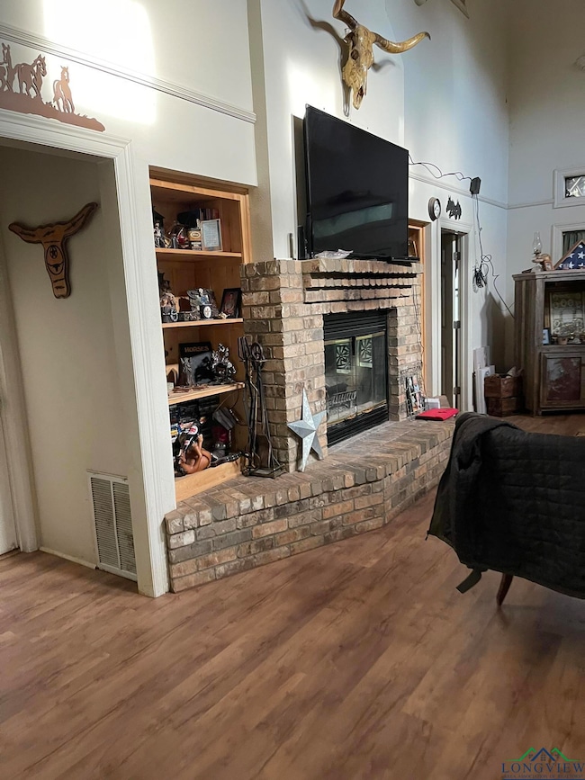 Living area with a brick fireplace, wood finished floors, and a high ceiling