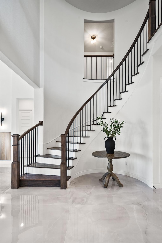 Staircase featuring a towering ceiling and baseboards