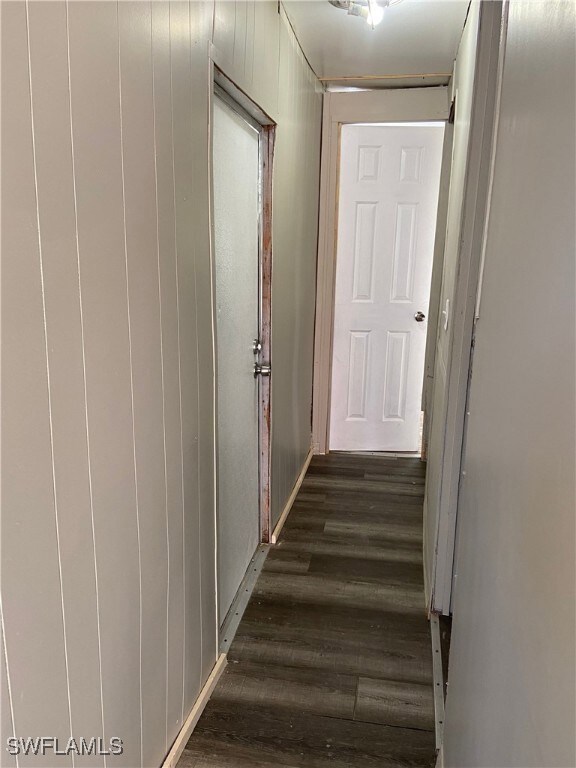 Corridor featuring dark wood-type flooring and wood walls