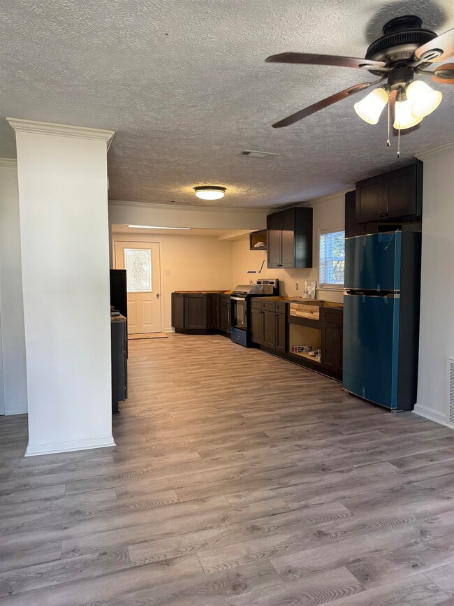 Kitchen with freestanding refrigerator, range with electric cooktop, light wood-type flooring, ceiling fan, and a textured ceiling