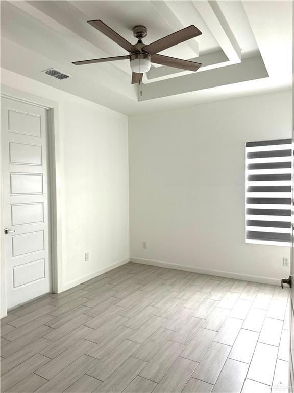 Spare room featuring a raised ceiling, wood finish floors, and ceiling fan