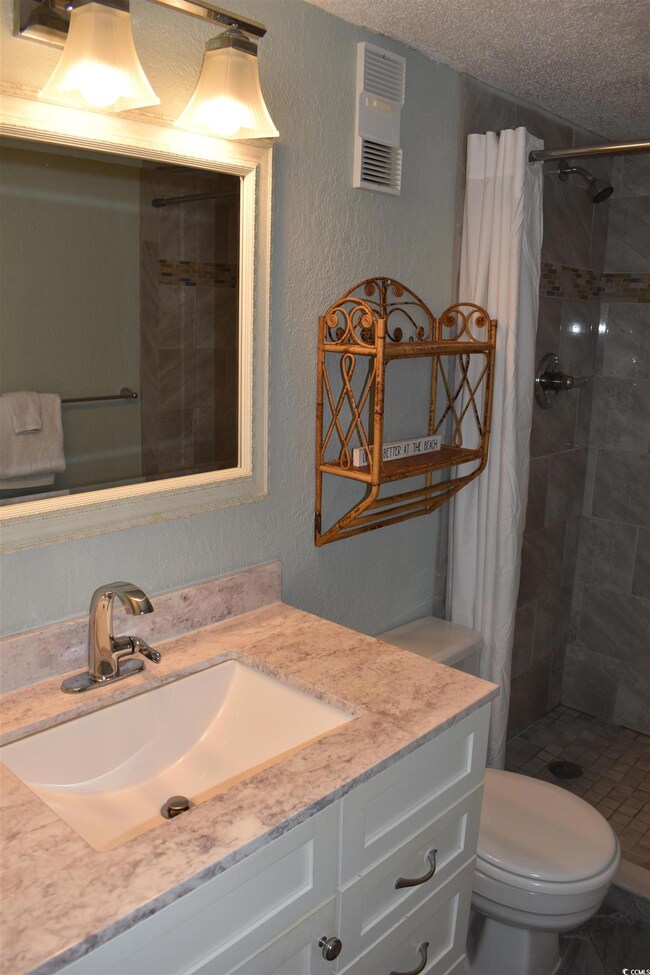 Bathroom with vanity, a textured ceiling, a shower