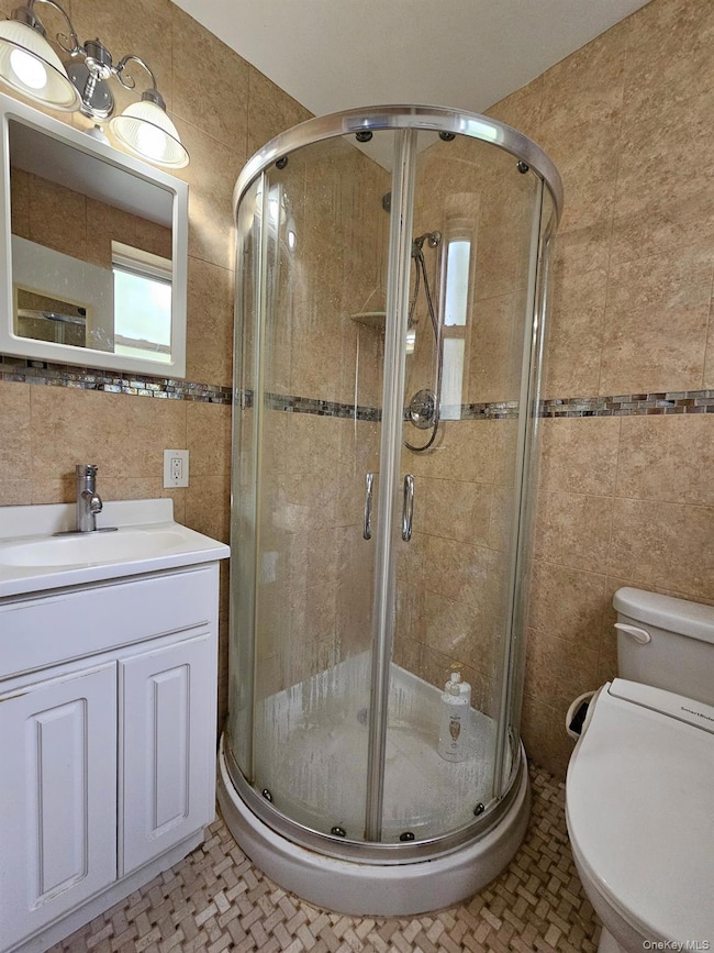 Bathroom featuring tile walls, vanity, and a stall shower