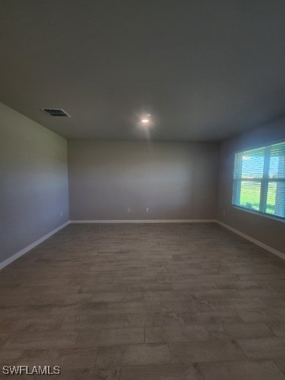 Unfurnished room featuring visible vents, baseboar