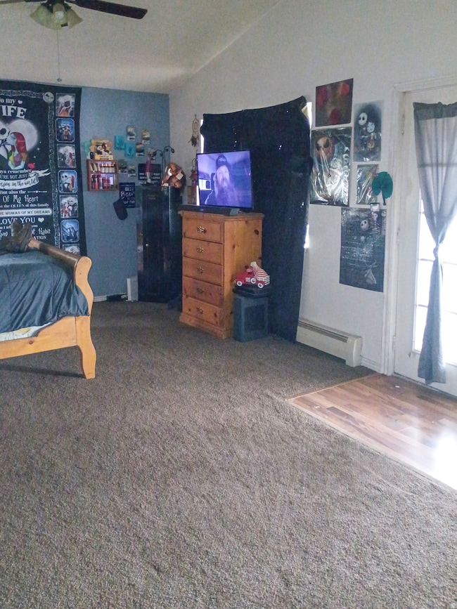 Bedroom with a baseboard radiator, carpet, and a ceiling fan