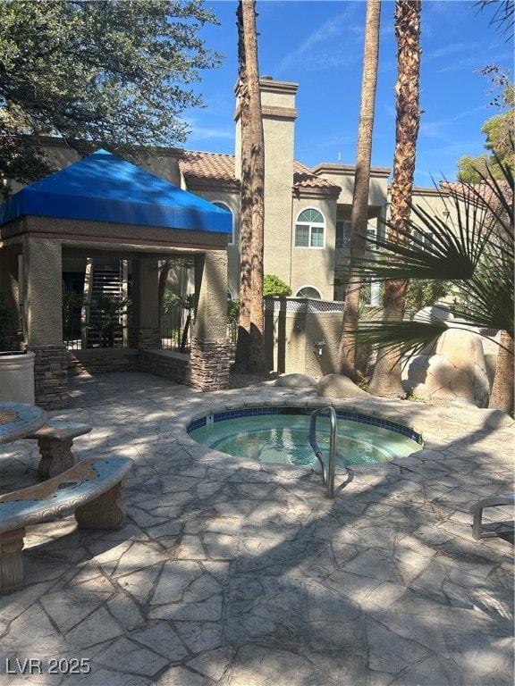 View of pool with a community hot tub, a swimming pool, and a patio