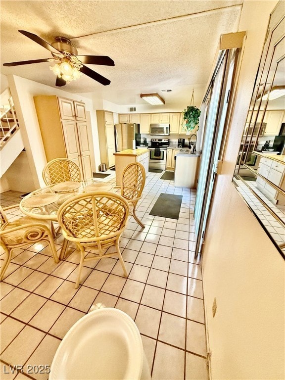 Dining space with ceiling fan, light tile patterned floors, and a textured ceiling
