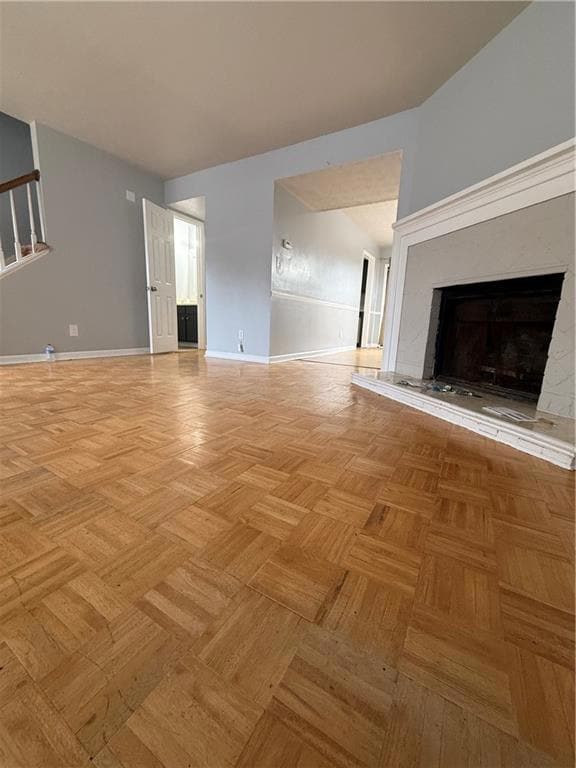Unfurnished living room featuring a premium fireplace and baseboards