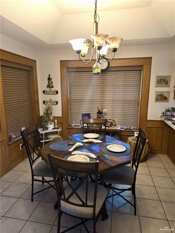 Dining area with wainscoting, light tile patterned flooring, a chandelier, and a textured ceiling