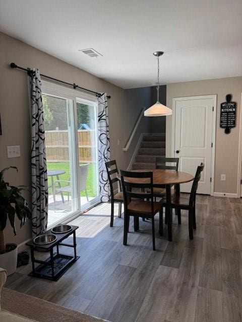 Dining area with stairs and dark wood-style floors